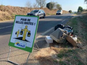un panneau sur le bord d'une route avec des déchets sur le côté
